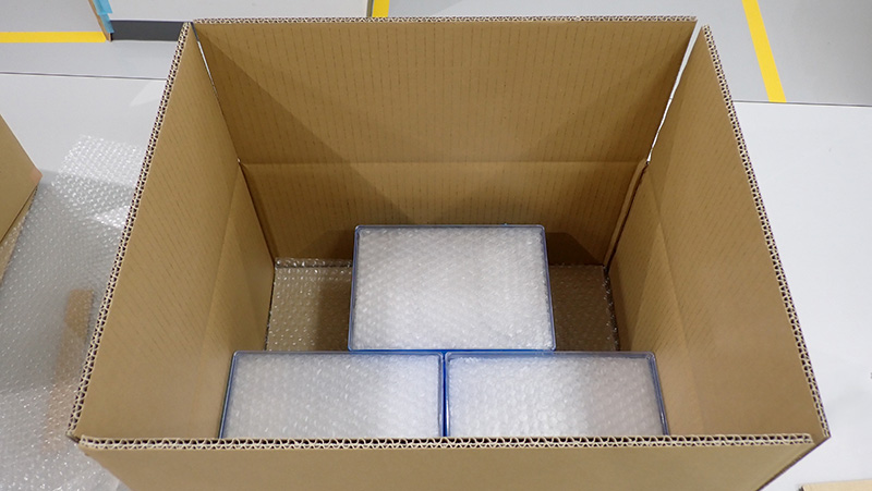 プラスチックケースを段ボールに並べた様子